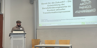 Burzlaff_Kiel.jpg Christoph Burzlaff steht an einen Podium vor einer Präsentation, die an der Wand projiziert wird. Der Titel der Präsentation wird abgebildet: "Bereit für die Zukunft? - Die Entwicklung der Berufsförderungswerke im Kontext aktueller Transformationsprozesse."